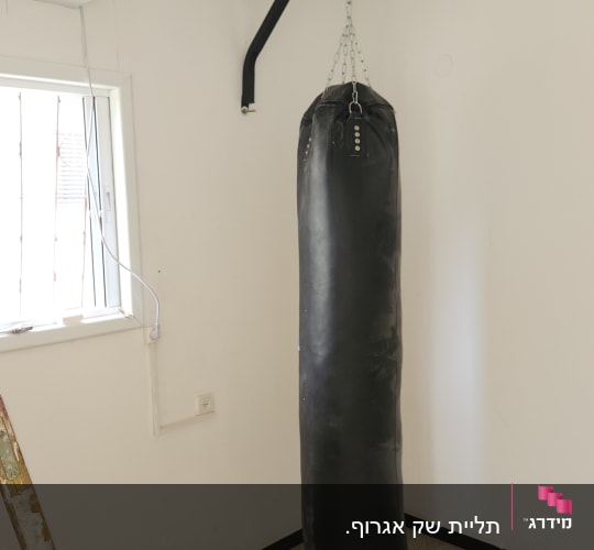 שק אגרוף תלוי על מתקן קיר עם סולם ליד